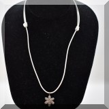 J135. White leather cord with pave diamond flower pendant.